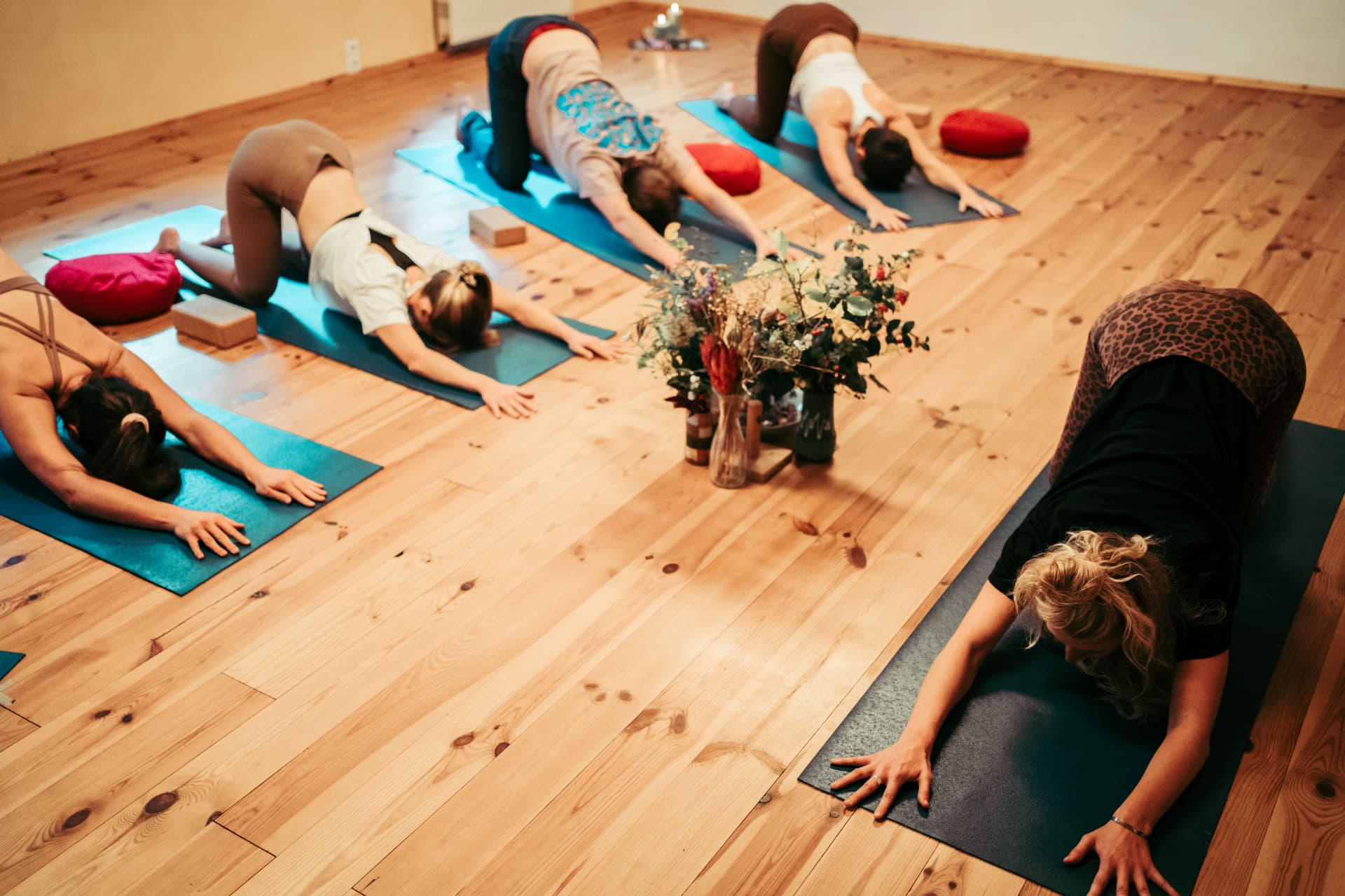 Yoga-Teilnehmende in einer entspannten Rückbeuge auf Yogamatten in einem warmen Holzraum