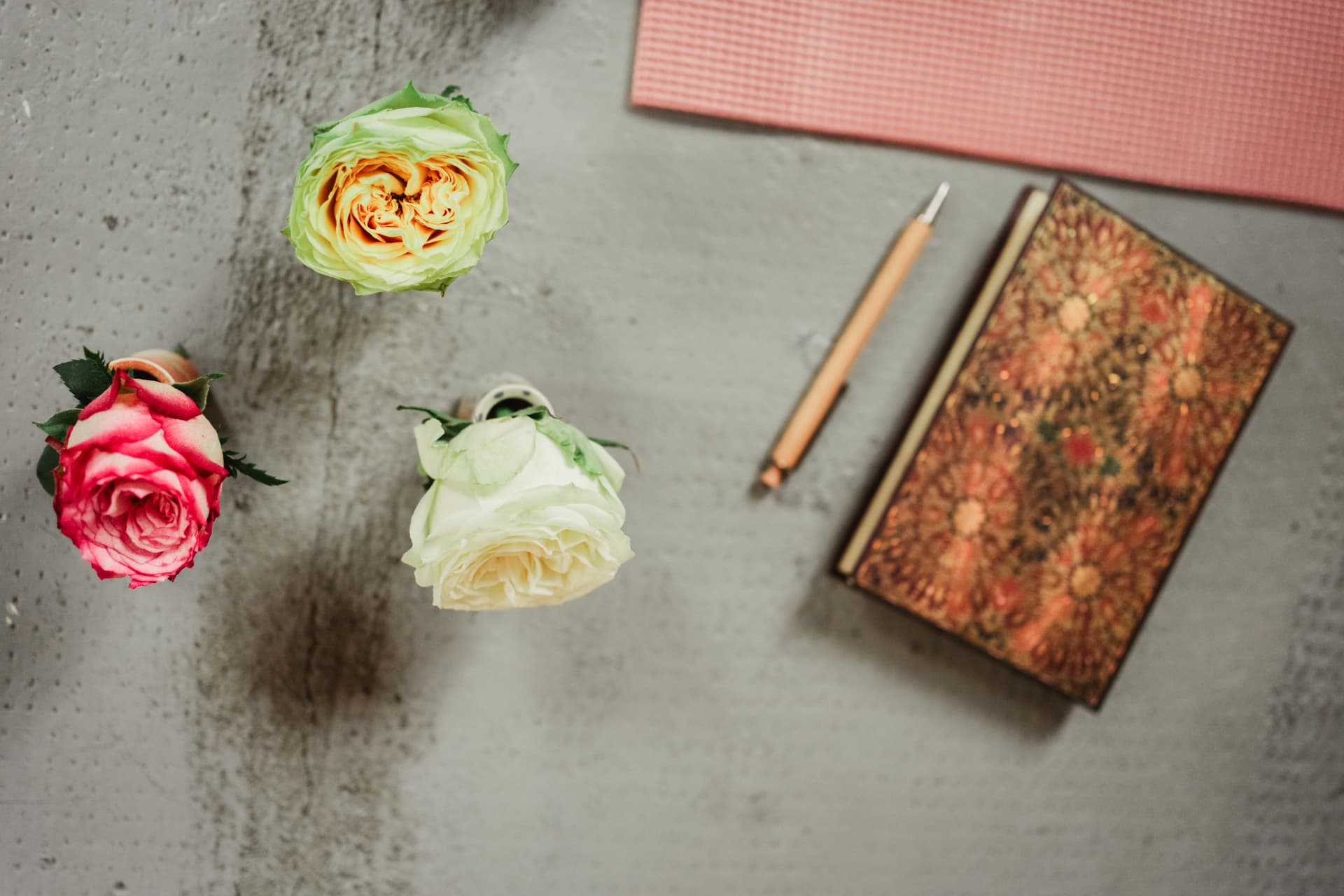 Rosen, Stift und Notizbuch neben einer Yogamatte